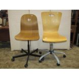 Two similar retro office chairs with moulded plywood seats, raised on swivel bases