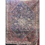 Antique Persian rug with central blue floral medallion framed by further scrolled foliage, 150 x 120