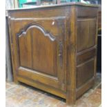 An 18th century oak side cupboard enclosed by a single arched and fielded panelled door, within a