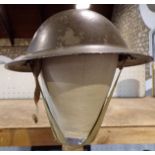 Vintage army helmet with green painted finish, upon a clamped hinged wig stand (2)