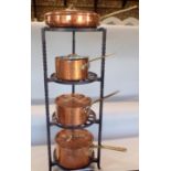 A cast iron pantry with three graduated planished copper lidded saucepans and further lidded pan (5)