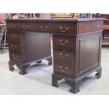 A reproduction Georgian style desk with inset leather top fitted with nine drawers, 120cm wide