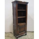 A small upright old English style open bookcase, fitted with two shelves, the lower cupboard door