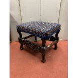 A Carolean style stool in oak with scrolled supports, carved frieze and hand worked tapestry top,