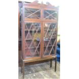 A Regency mahogany cabinet enclosed by two pairs of glazed panelled doors, raised on an open