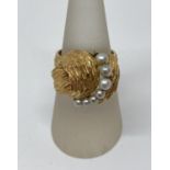 Stylised gold ring set with graduated pearls, foreign stamps to outer shank, size O, 6.9g