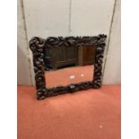 A Carolean style carved oak wall mirror, with cherub, scroll, lion mask and other detail, 67cm