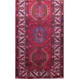 A good long Heriz runner with faceted floral and other medallion patterns upon a red ground, 420 x