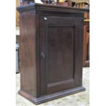 An antique oak side cupboard enclosed by a rectangular moulded panelled door with two removable