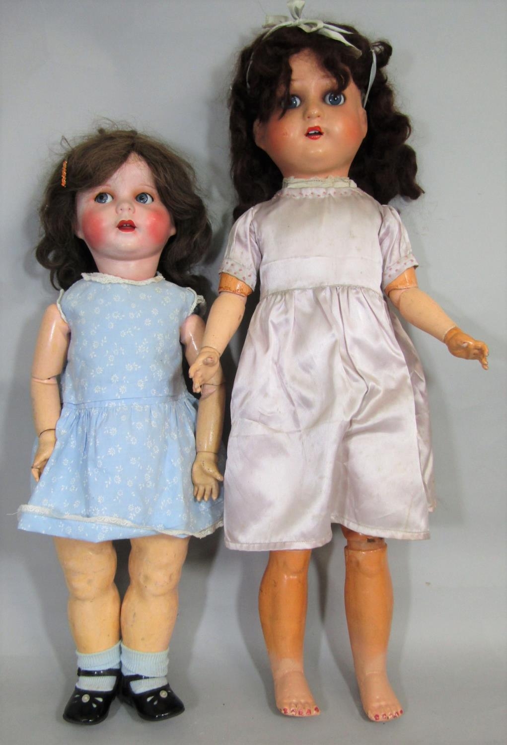 2 early 20th century large composition head dolls, both with closing blue eyes, the taller doll 75cm