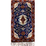 Small full pile Persian rug with central cream and orange medallion upon a blue ground, 125 x 60cm