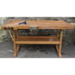 A beechwood work bench with three vices, cut out receptacles and overhanging top raised on square
