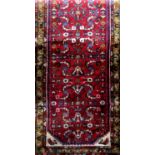 Persian runner with geometric medallion decoration upon a red ground, 190 x 70cm