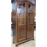 A mahogany side cabinet freestanding and enclosed by a pair of full length partially glazed panelled