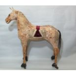 A large folk art horse made from wood, vellum and composition, on castors, with glass eyes,