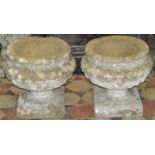 A pair of reclaimed garden urns of squat circular form, with studded collars, and repeating fleur de