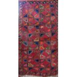 Unusual small Persian rug with geometric decoration upon a deep red ground, 110 x 50cm