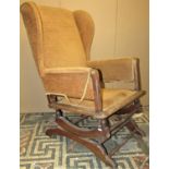 A vintage upholstered wing back sprung rocking chair with moulded and turned framework