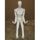 A painted life size female fashion shop display mannikin in seated pose with moveable arms