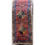 Antique Afghan runner with four diamond shaped medallions upon a washed red ground with floral