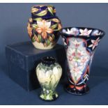 A Moorcroft vase of flared form with stylised white and pink lily type flowers on a blue ground,