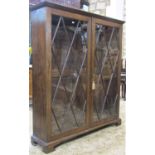 A Georgian style oak side cabinet freestanding and enclosed by a pair of rectangular astragal glazed