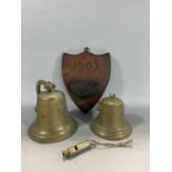 Two antique brass bells together with a whistle inscribed '1915' and an antique oak wall pocket