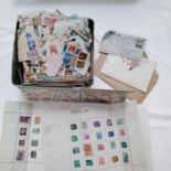 A box containing a large quantity of loose and sorted stamps, postcards, pages from stamp albums,