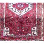 Persian full pile rug with central floral red and green medallion framed by further scrolled foliage