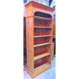 A waxed pine freestanding bookcase, set within an arched outline, 200cm x 90cm
