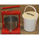 A small table top apple fruit press with red painted steel frame together with an associated