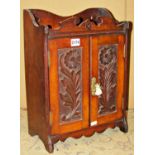 A late Victorian/Edwardian oak wall mounted smokers cabinet enclosed by a pair of carved floral