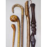 Mixed collection of walking sticks, four rustic examples, a carved tribal hardwood stick and a