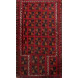 Old Baluchi village rug with geometric harlequin medallion decoration upon a red ground 150 x 85 cm