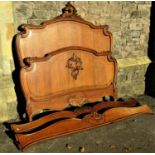 A panelled oak double bedstead with shaped and moulded outline and scrolling acanthus detail and