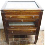 An oak opticians cabinet, the rising lid with glass panel, revealing an adjustable tray containing a