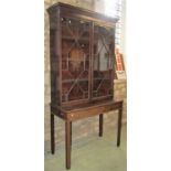 A mahogany side cabinet enclosed by a pair of astragal glazed panelled doors, resting on a table