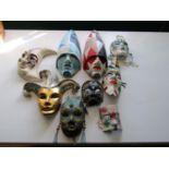 Nine papier mache Venetian masks, together with four small ceramic wall masks