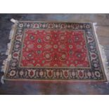 An eastern wool red ground rug, with abstract floral detail, set within an ink blue running border