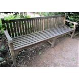 A weathered teak wood garden bench, 240cm wide