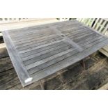 A good quality weathered teak garden table with slatted top and folding x shaped frame, 155cm x 95cm