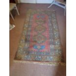 An eastern wool rug, with triple medallion centre upon a pink field, set within running geometric