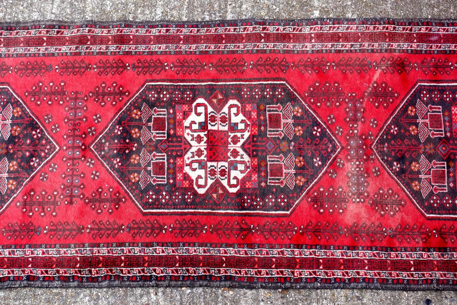 Oriental carpet runner, with three central medallions, on a deep red ground, 274 x 78 cm - Image 2 of 3