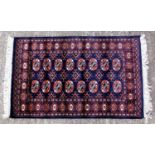 Eastern carpet with geometric repeat pattern on a dark background, 130 x 79 cm plus fringe.