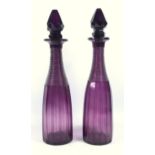 A pair of Victorian amethyst glass decanters, with step cut and faceted decoration, H. 36 cm.