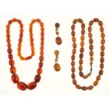 Two vintage necklaces, an oval amber bead necklace 66 cm, a red lucite bead necklace, and a pair