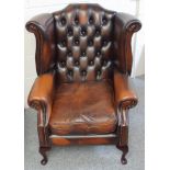 George III style winged armchair with a buttoned back and loose seat cushion upholstered in brass