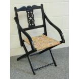 Edwardian black lacquered folding armchair with a pierced splat back and floral seat, oak firescreen