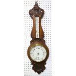 An Edwardian carved oak aneroid barometer, with thermometer and circular dial, 88cm long