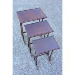 A mahogany nest of three occasional tables with shallow galleried tops on dual spindle supports to